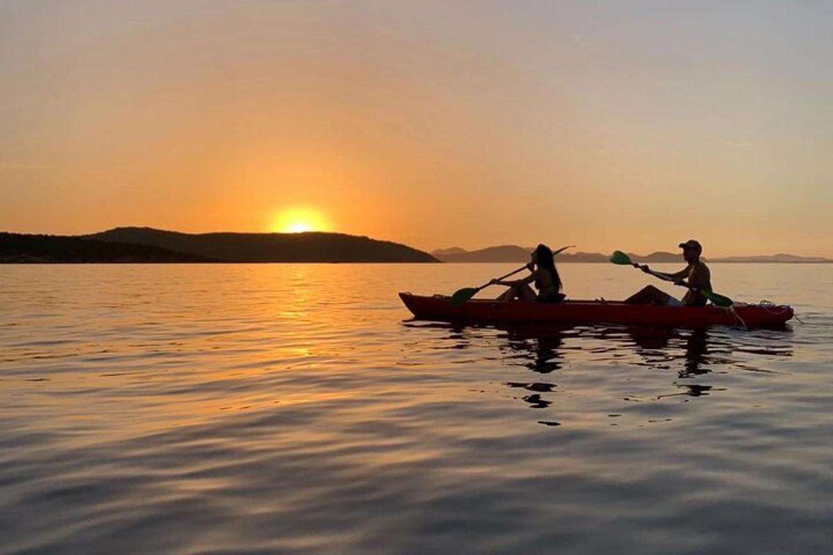 two people in a kayak on the water at sunset