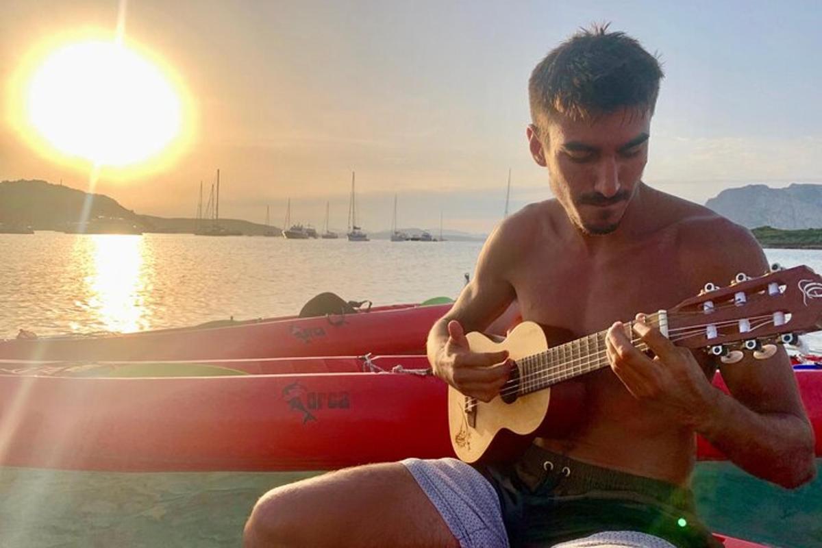 a man sitting on a boat playing a guitar