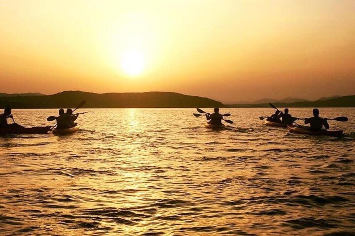 a group of people kayaking on the water at sunset