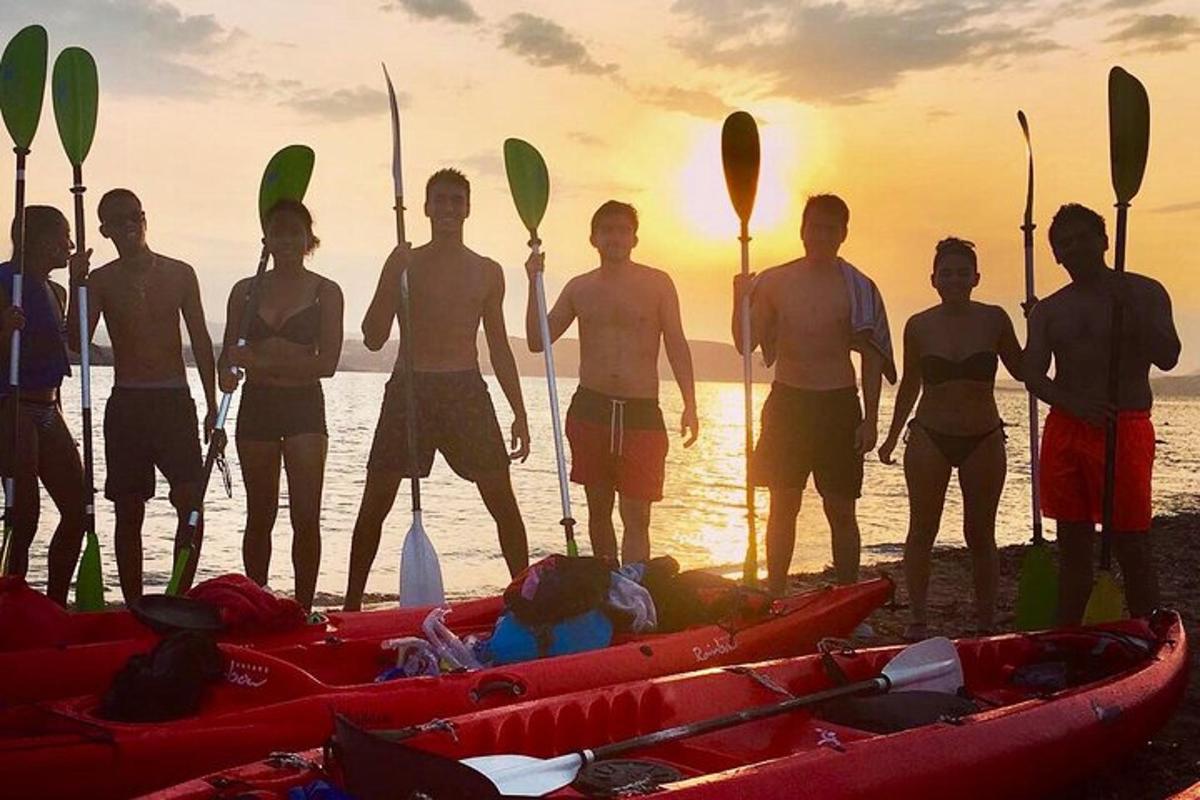 a group of people standing on the beach with kayaks