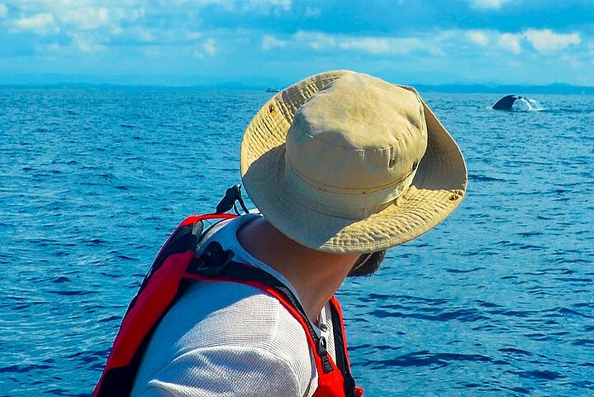 muž v slaměném klobouku s výhledem na oceán