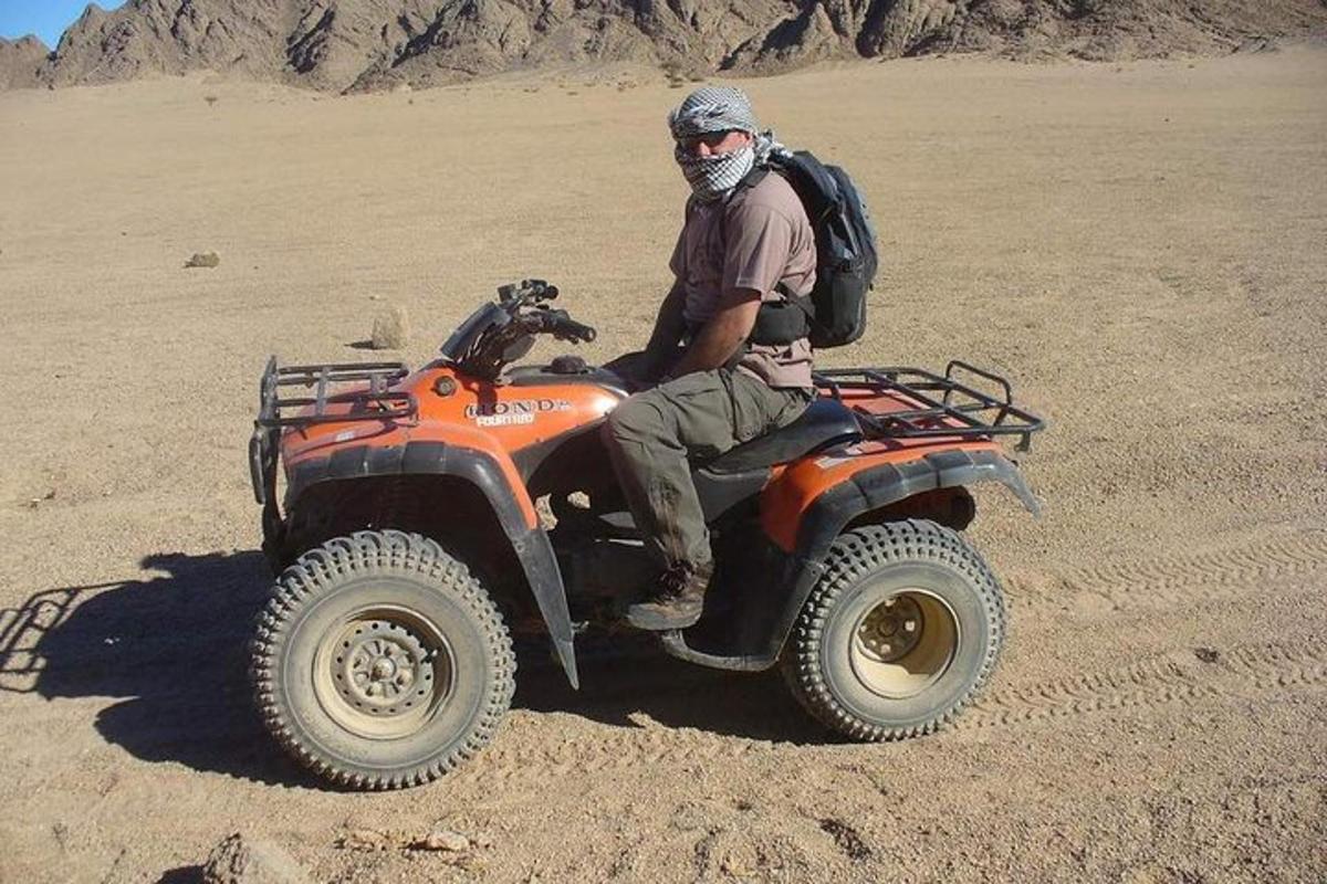 um homem sentado em um quadriciclo no deserto
