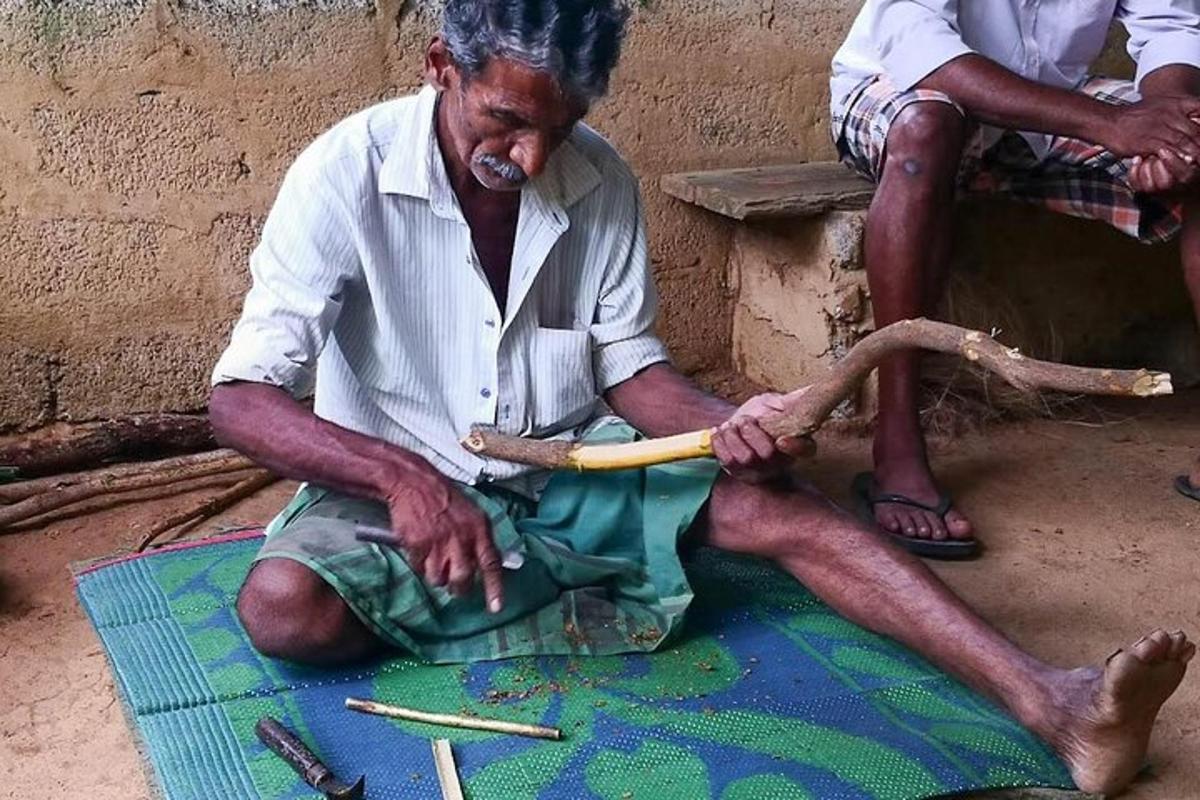 a man sitting on the ground holding a stick