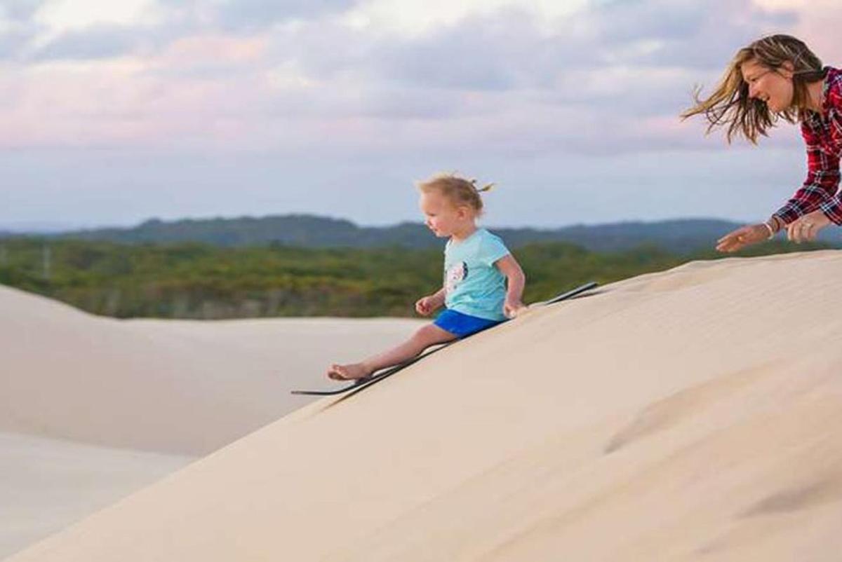a woman and a child sitting on a sand hill