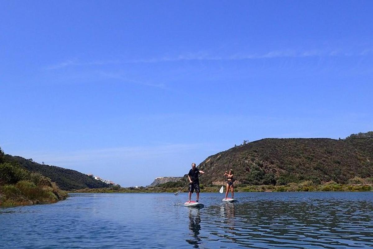 două persoane stau pe plăci de paddle în apă