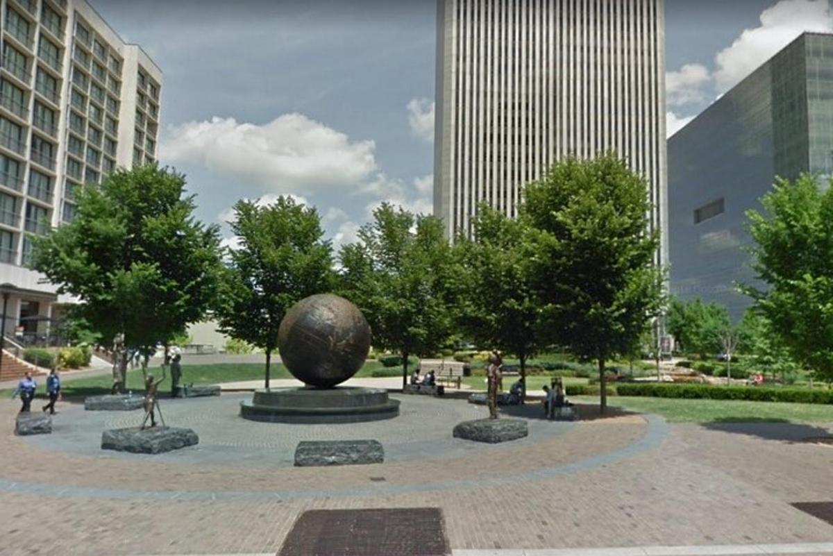 una escultura en un parque con árboles y edificios
