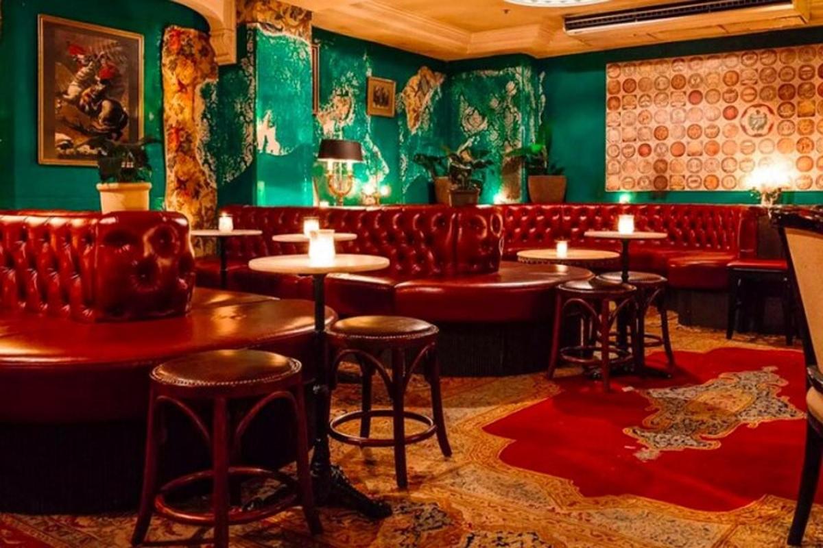 Un bar con asientos de cuero rojo, mesas y sillas.