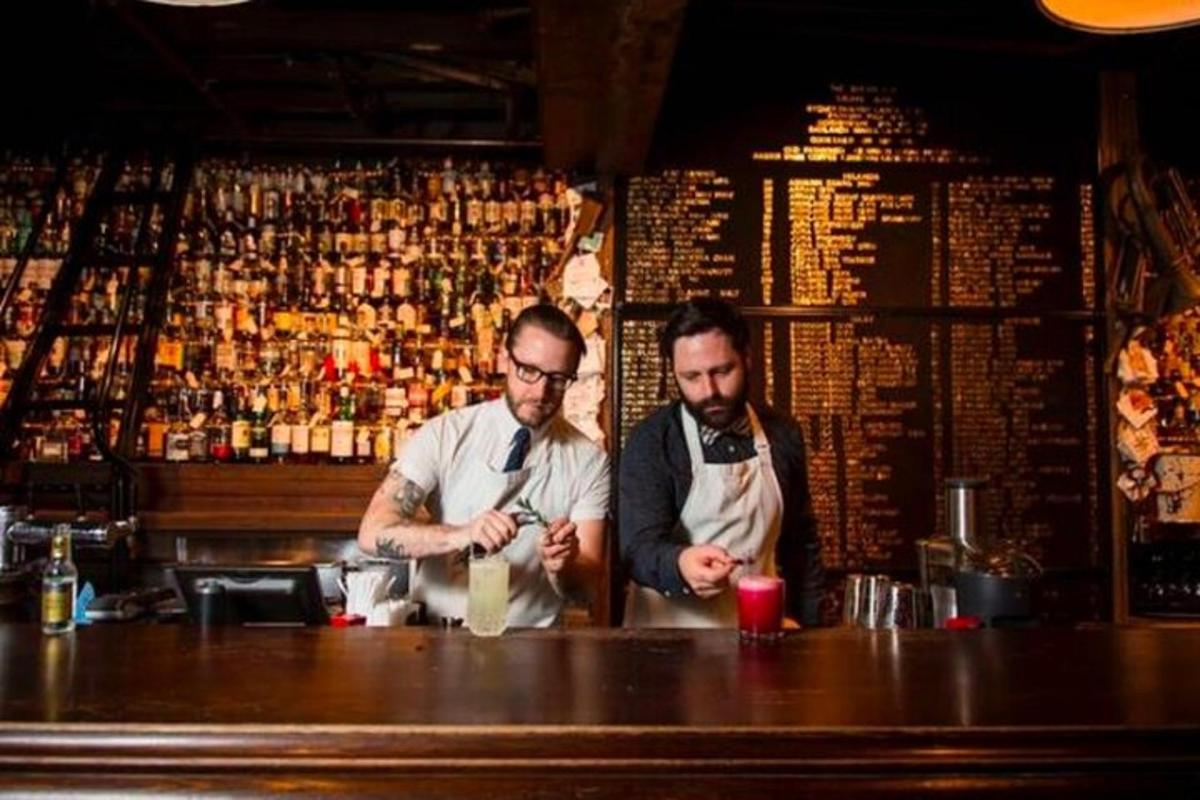 hai người đàn ông đứng sau quầy bar trong một quán rượu