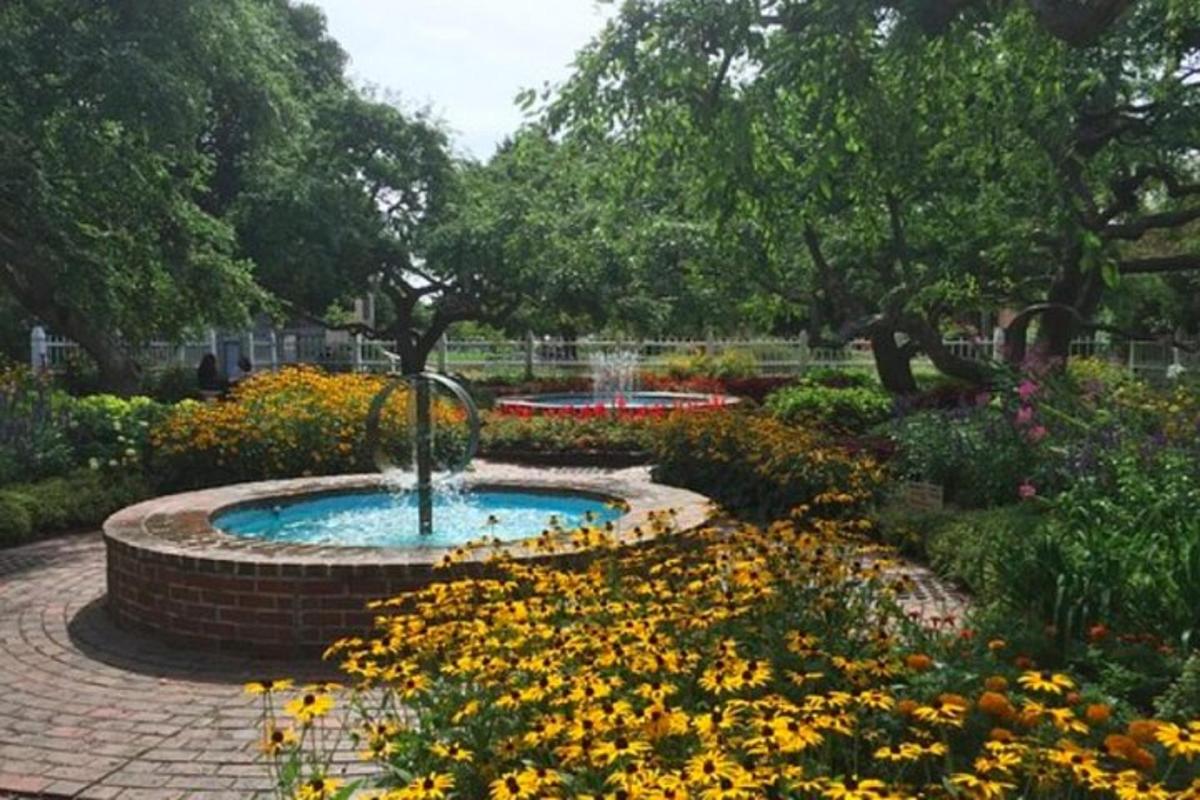 a fountain in a garden with flowers and trees