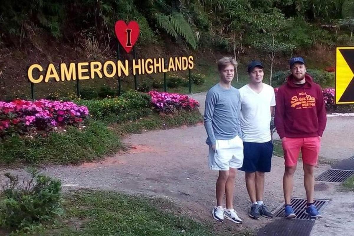 a group of three men standing in front of a sign