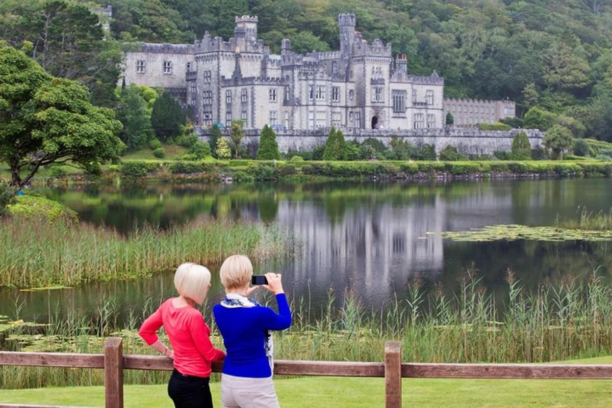 two women taking a picture of a castle over a lake
