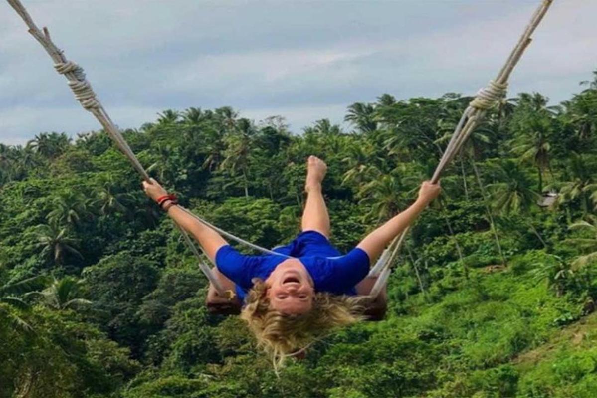 una donna che si dondola su un'altalena di corda davanti agli alberi