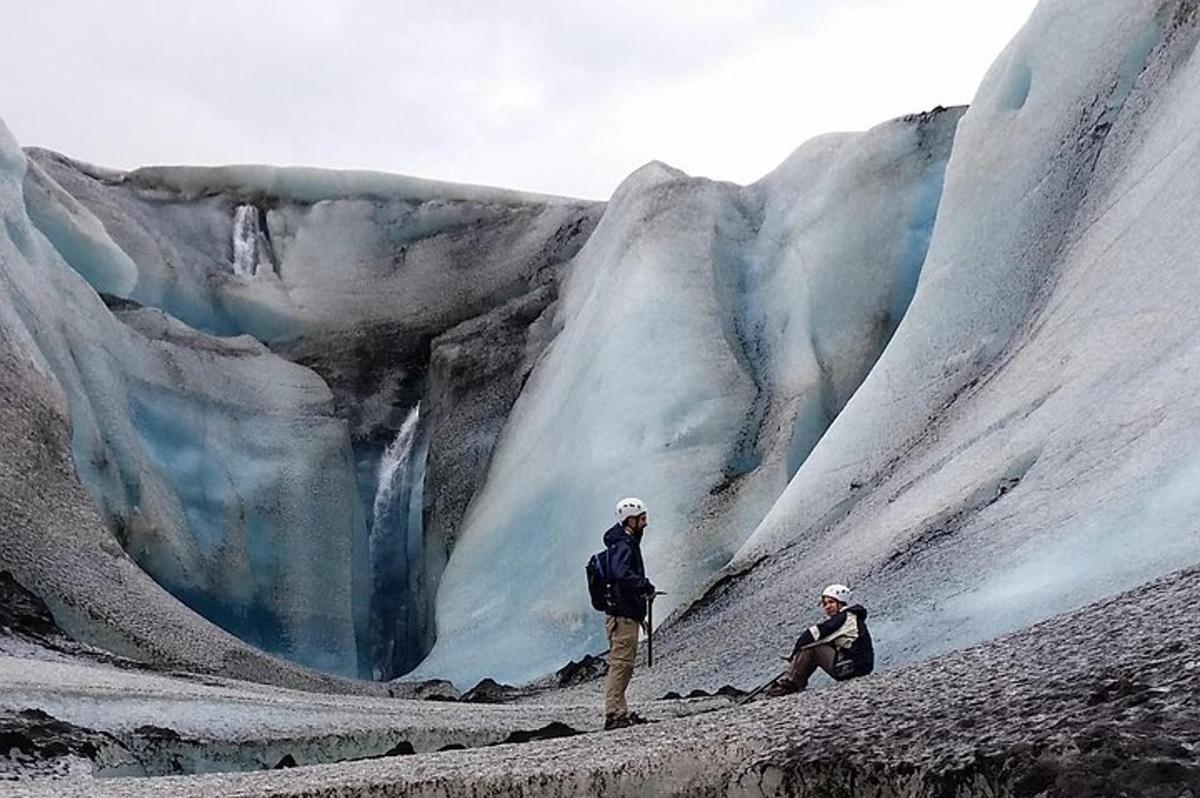 two people are standing in front of a glacier