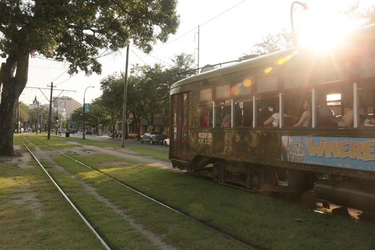 a trolley car driving down a street with the sun shining