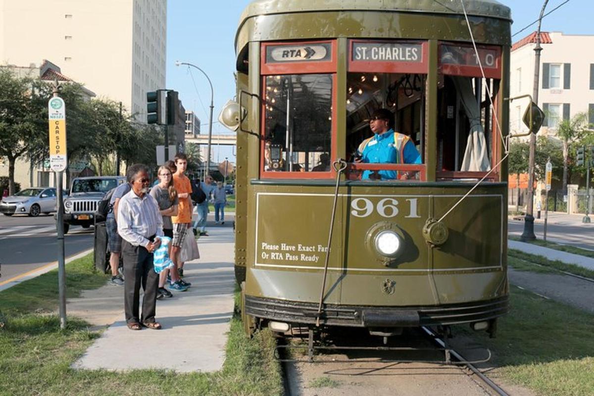 a trolley car on a street with people waiting to board