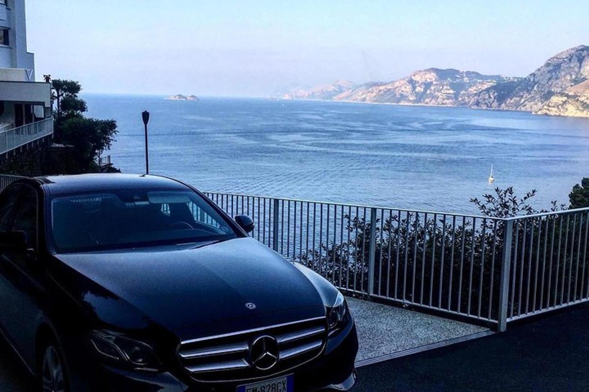 a black car parked next to a fence near the ocean