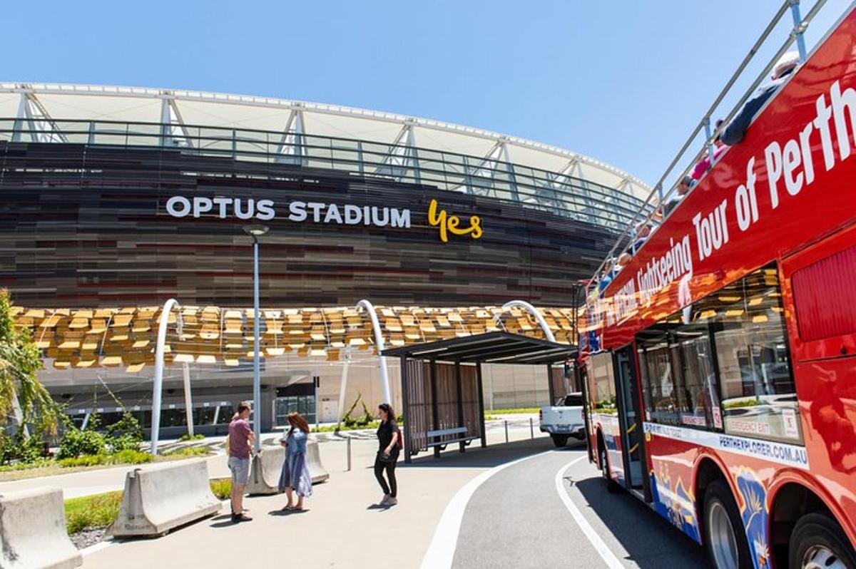 a red bus parked in front of a stadium
