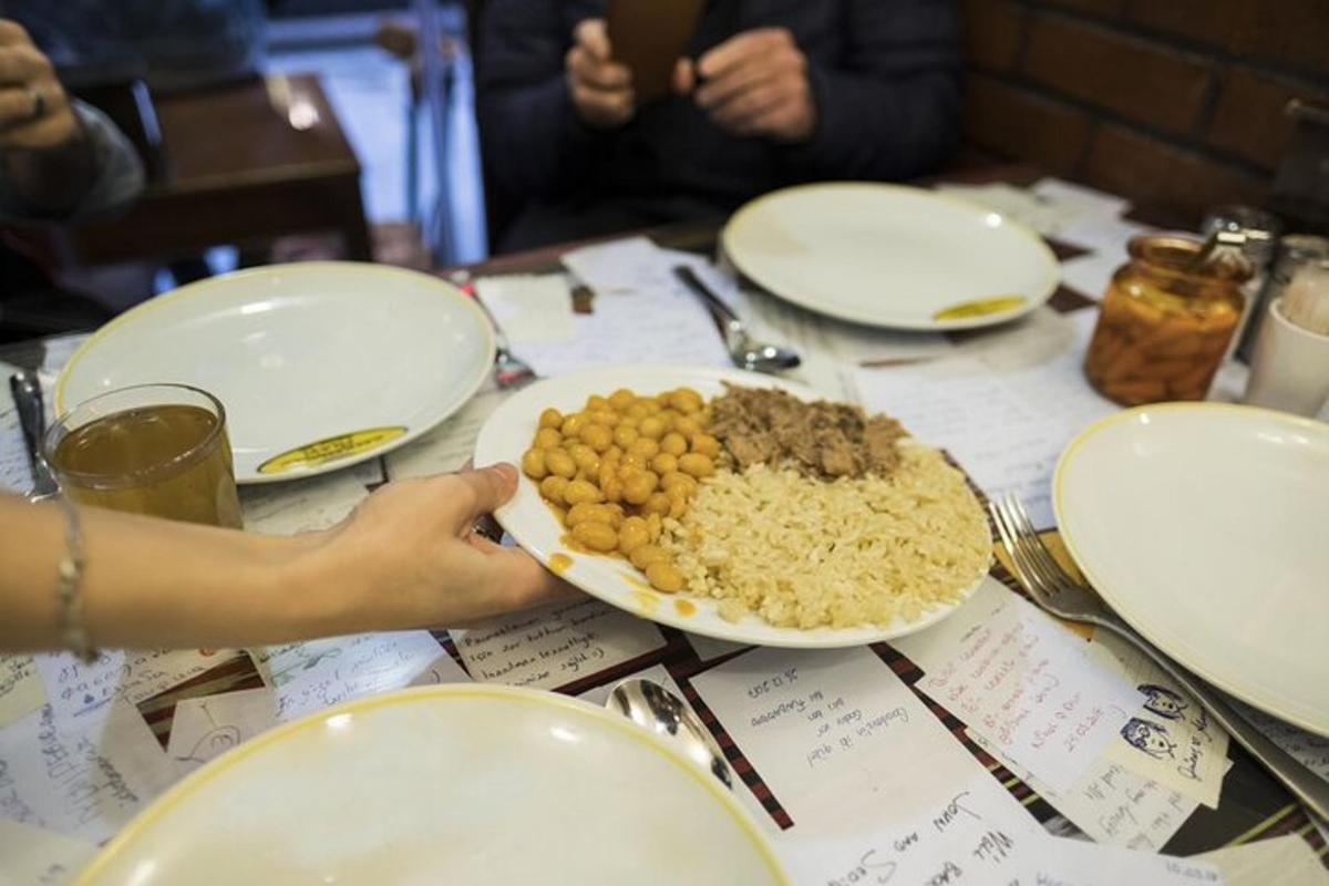 ένα άτομο που κρατά ένα πιάτο με φαγητό σε ένα τραπέζι