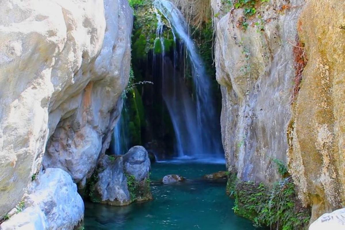a waterfall in a canyon with a pool of water