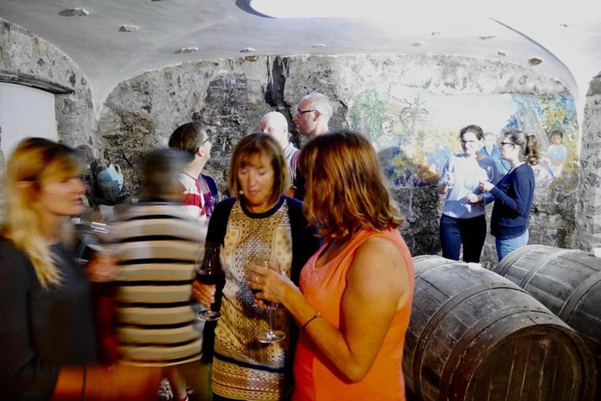 un grup de persones dretes al voltant d'una habitació amb bótes de vi