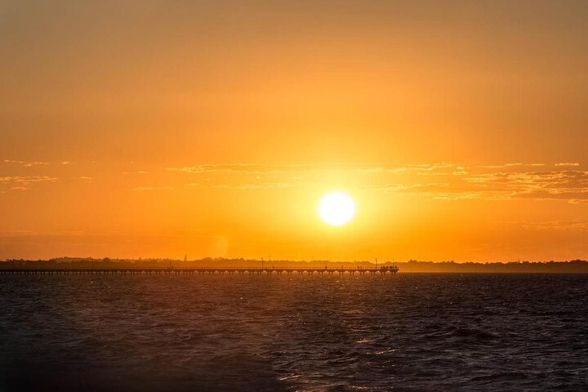 una posta de sol sobre una massa d'aigua amb un moll