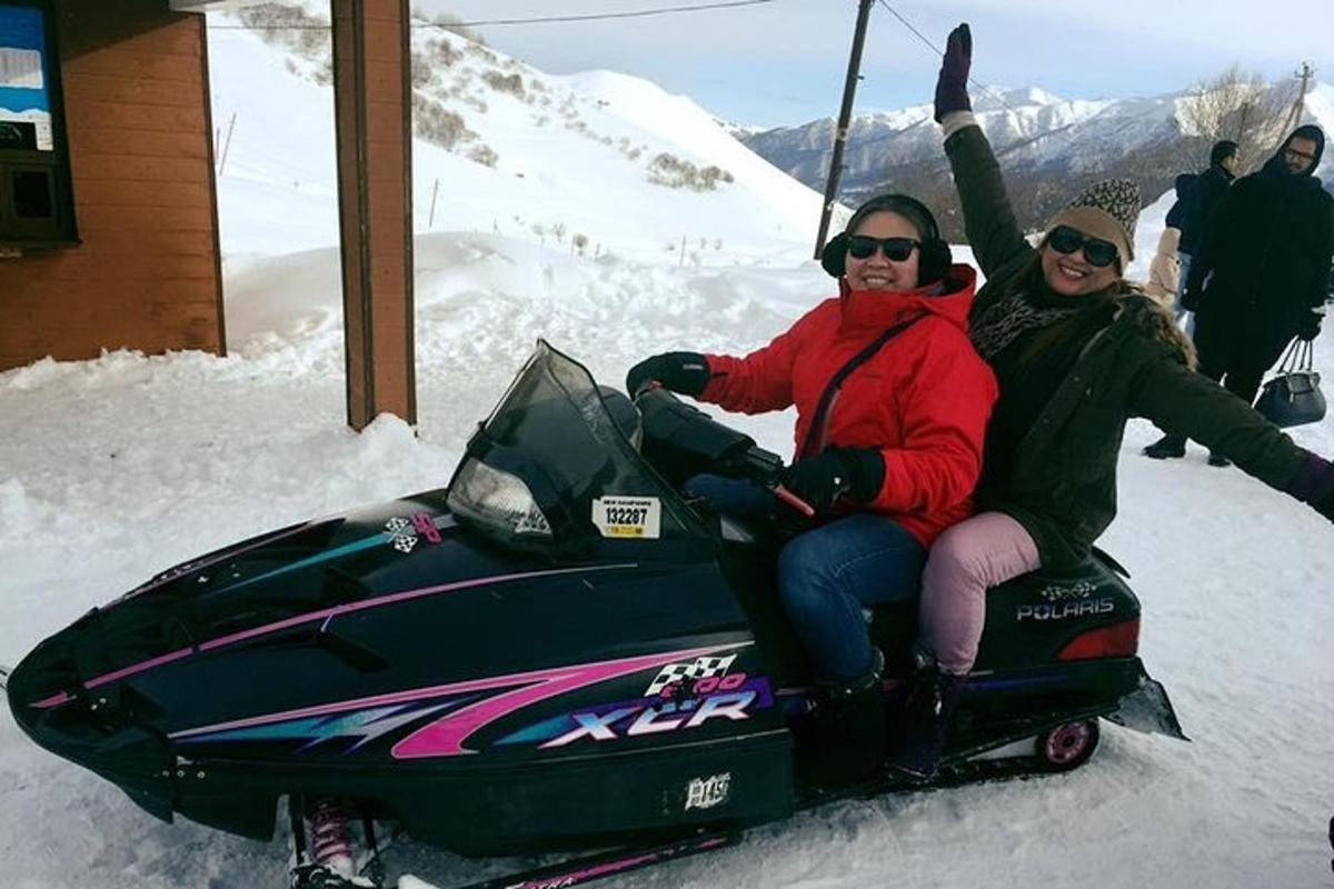 two people sitting on a snowmobile in the snow