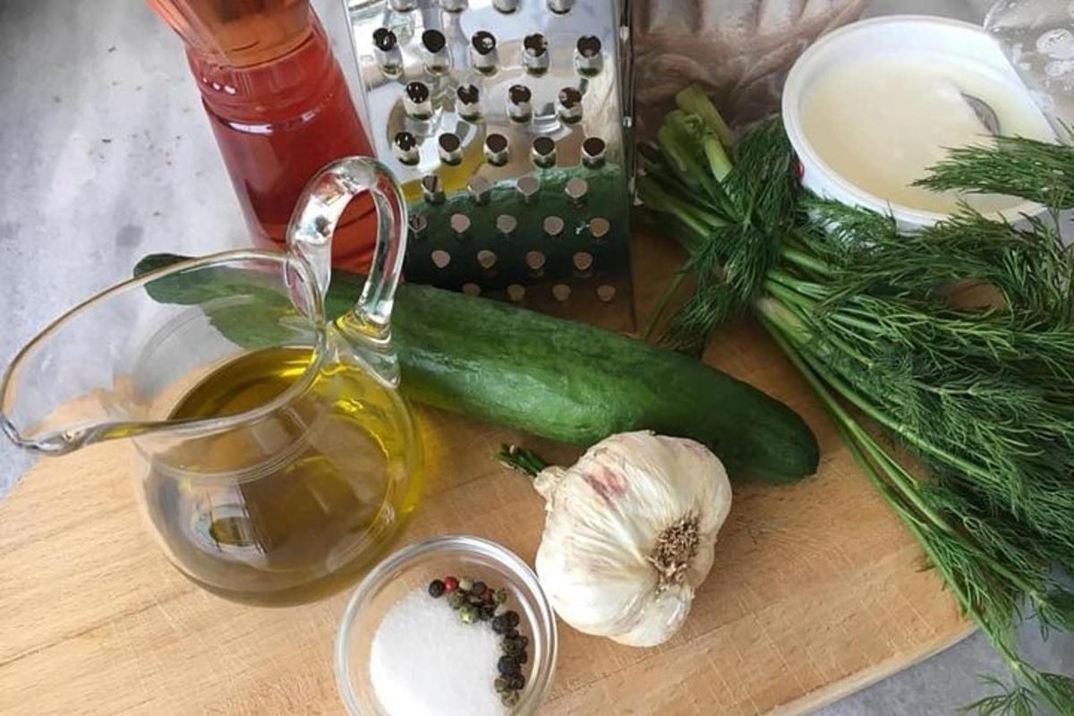 Una tabla de cortar con un pepino verde y una taza de té.