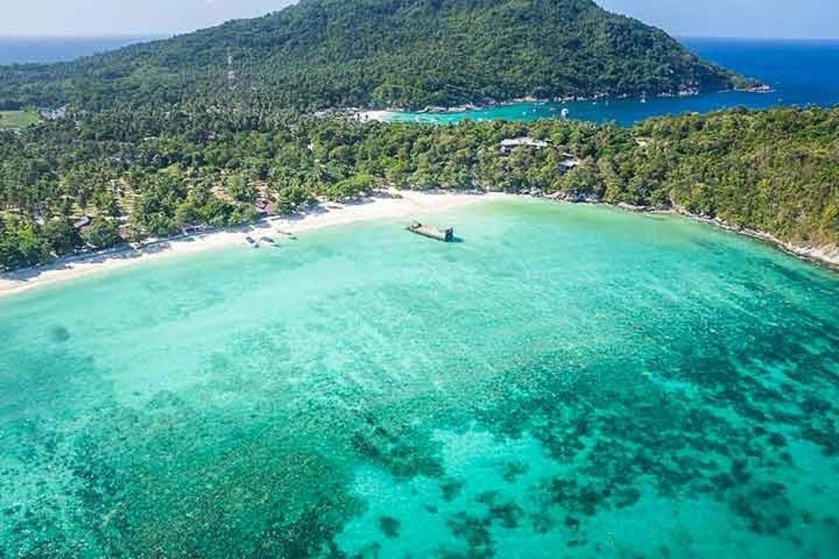 an aerial view of a beach with a boat in the water