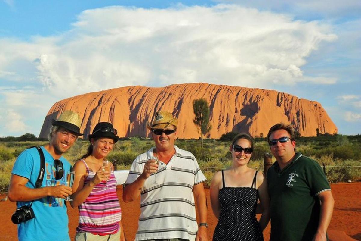 un grup de oameni care stau în fața Ayers Rock