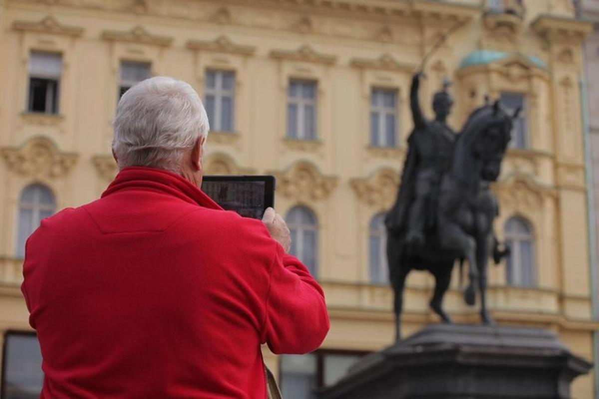 muž fotografující sochu před budovou