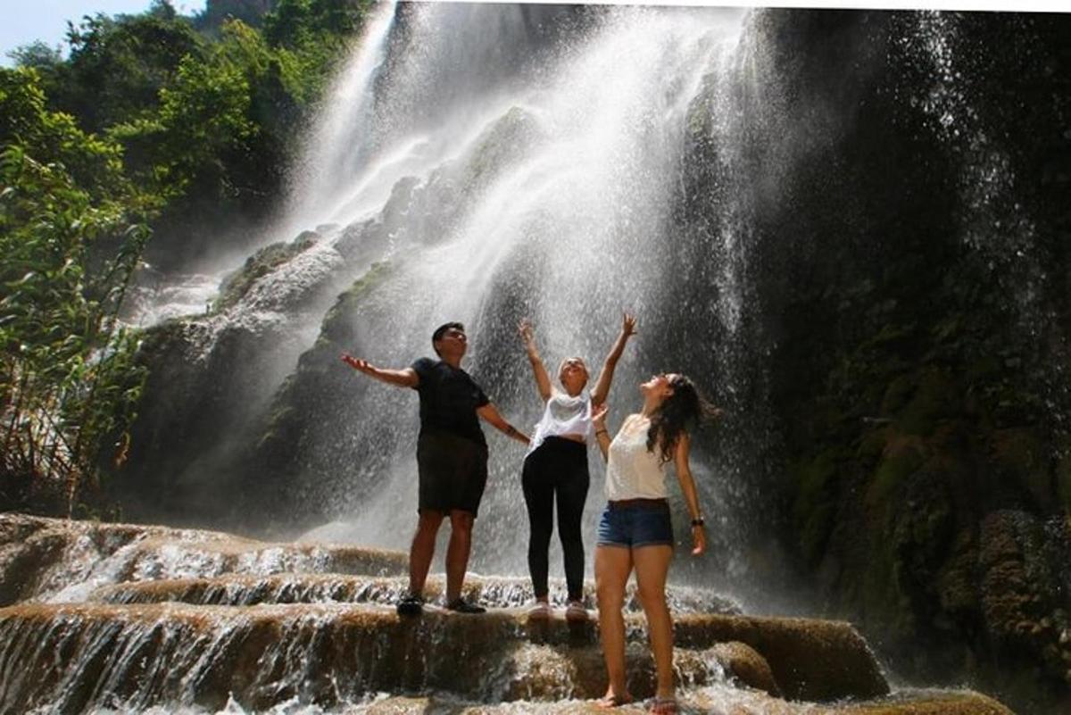 three people standing in front of a waterfall