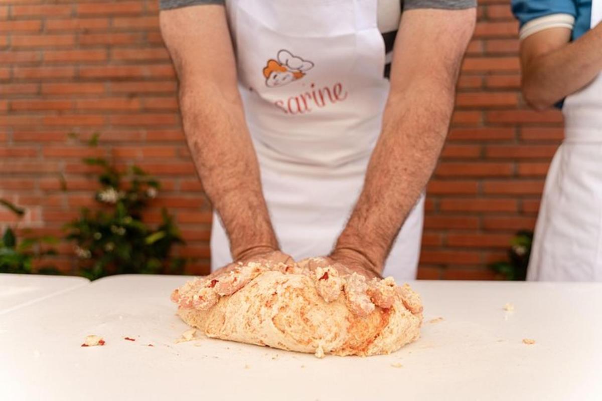 un uomo con un grembiule che tiene un pezzo di pane su un tavolo