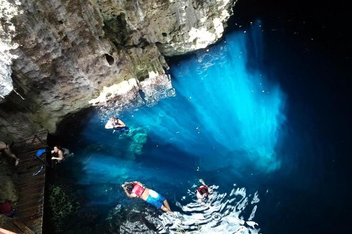 sekumpulan orang berenang di dalam air berhampiran sebuah gua