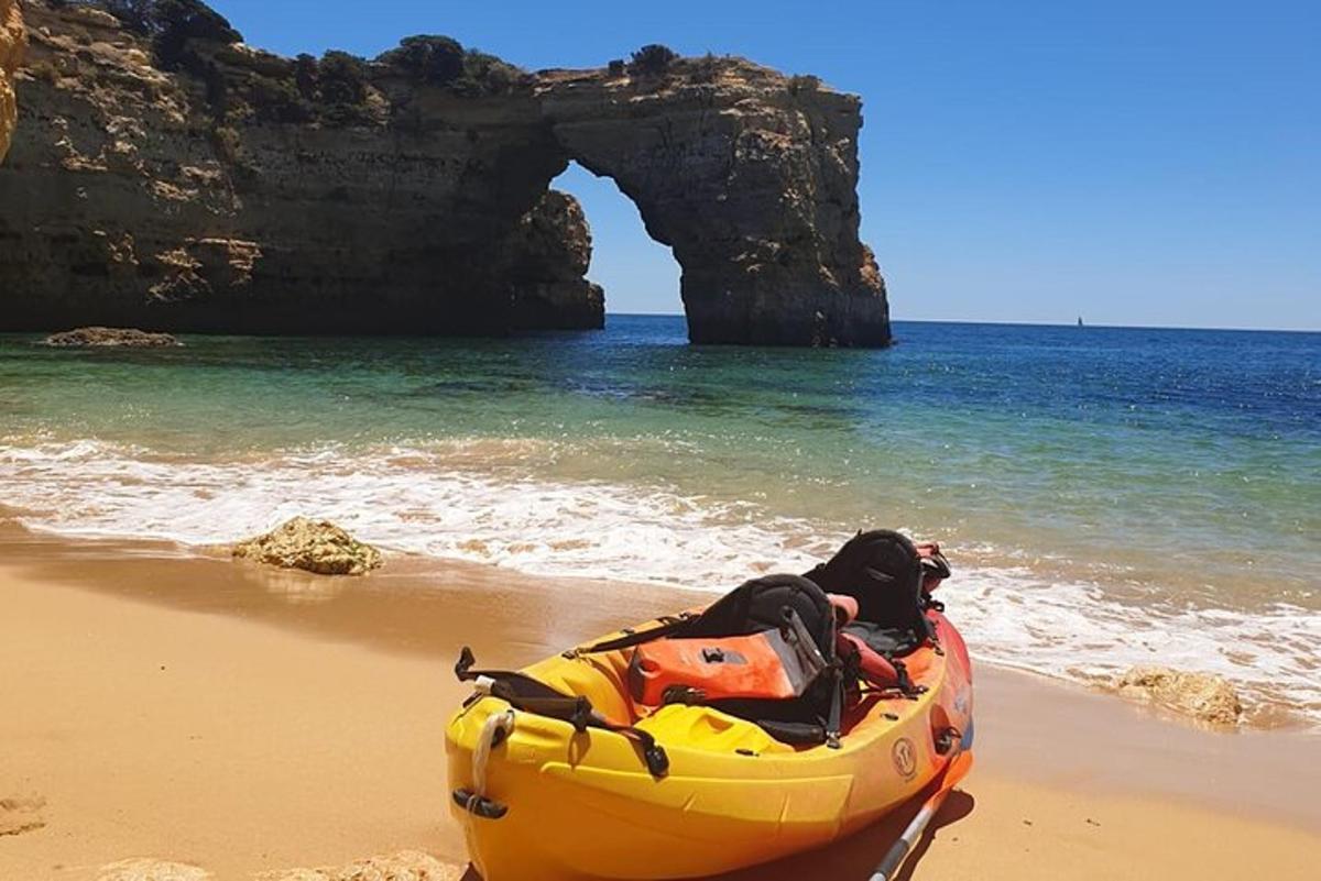 a yellow kayak on a beach with an arch in the water