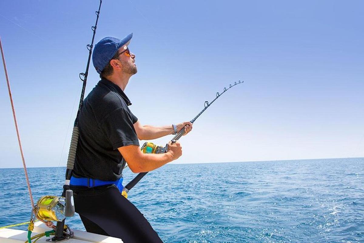 en mann som holder en fiskestang på en båt i havet