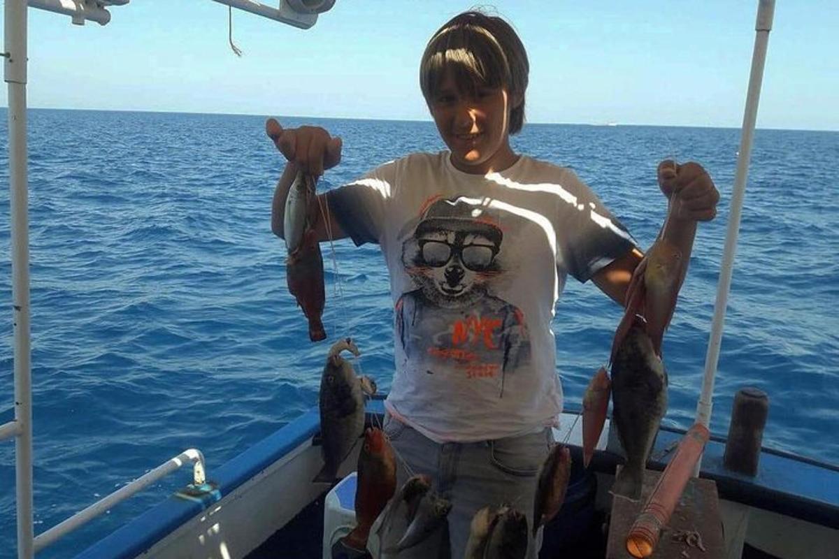 en mann som står på en båt og holder en haug med fisk