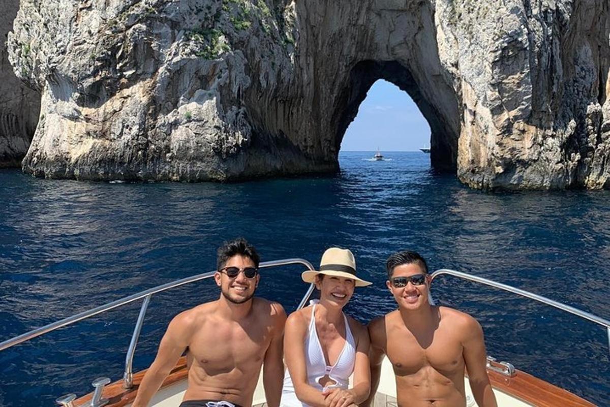 three men and a woman on a boat in front of a cave