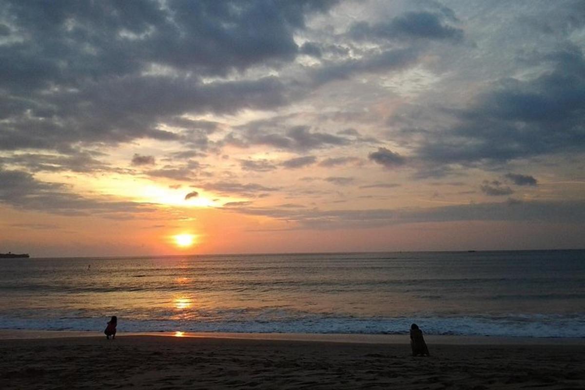 dva človeka, ki se sprehajata po plaži ob sončnem zahodu
