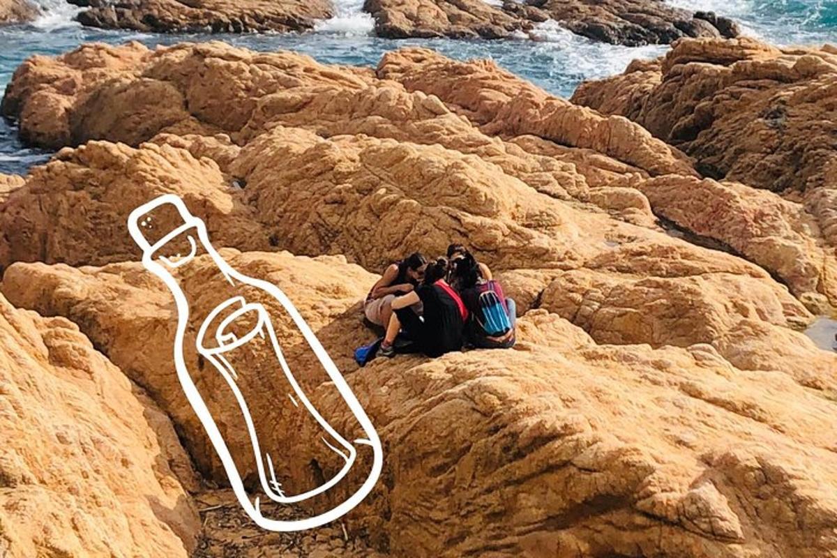 three people sitting on the rocks near the water