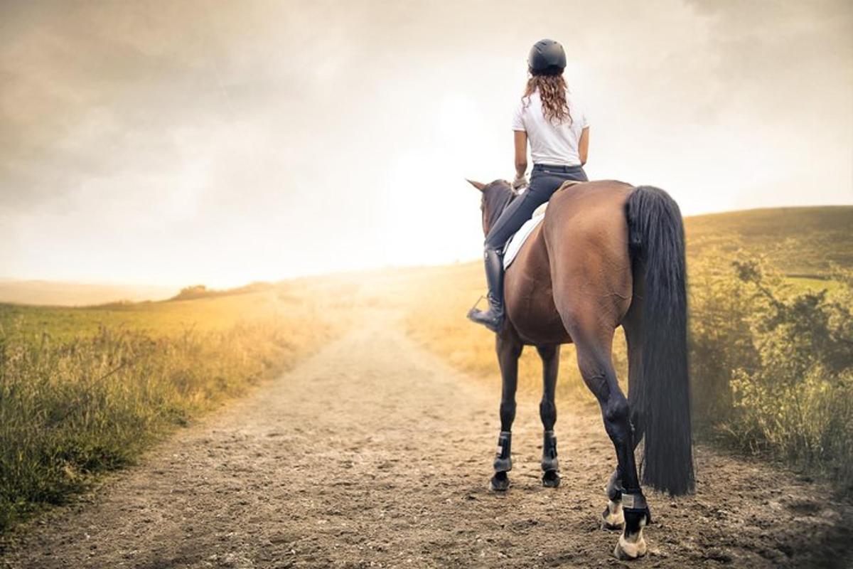 una donna a cavallo lungo una strada sterrata