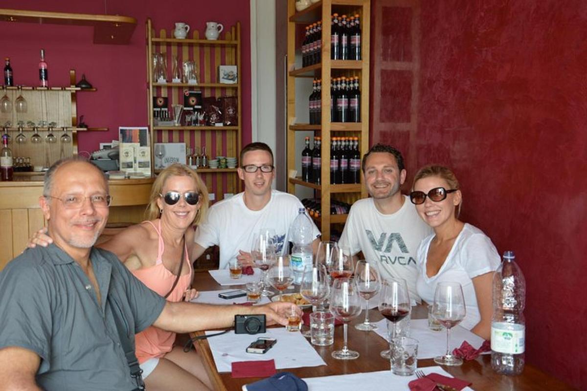 skupina ljudi, ki sedijo za mizo z vinskimi kozarci
