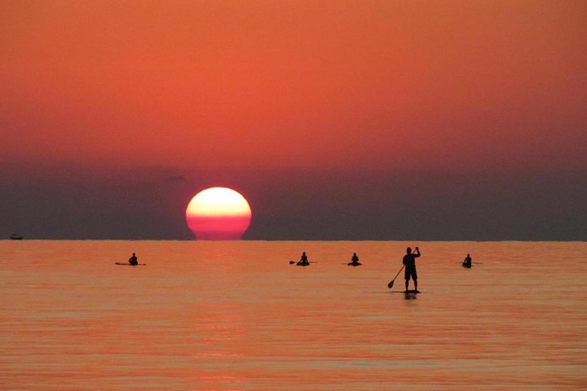 Ένα άτομο σε σανίδα κουπί στον ωκεανό κατά το ηλιοβασίλεμα