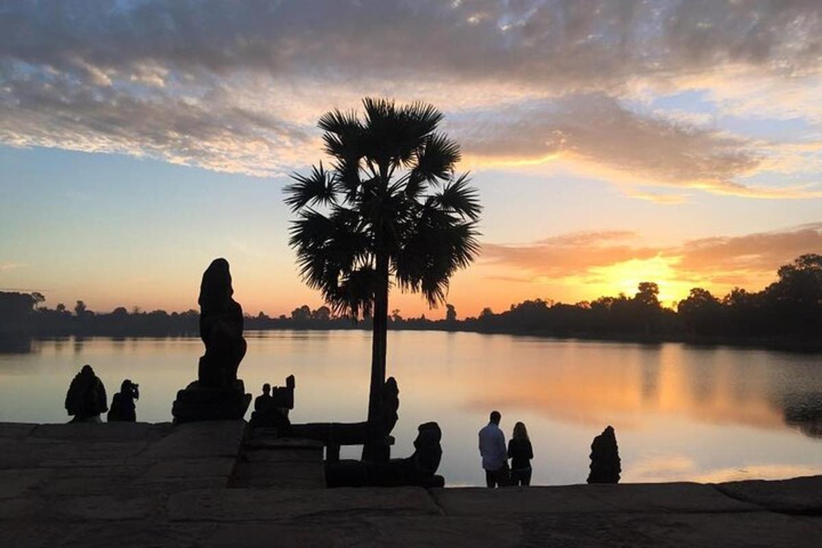 sekumpulan orang duduk di hadapan tasik pada waktu matahari terbenam