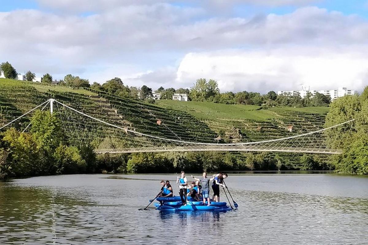 un gruppo di persone in barche su un fiume con un ponte sospeso