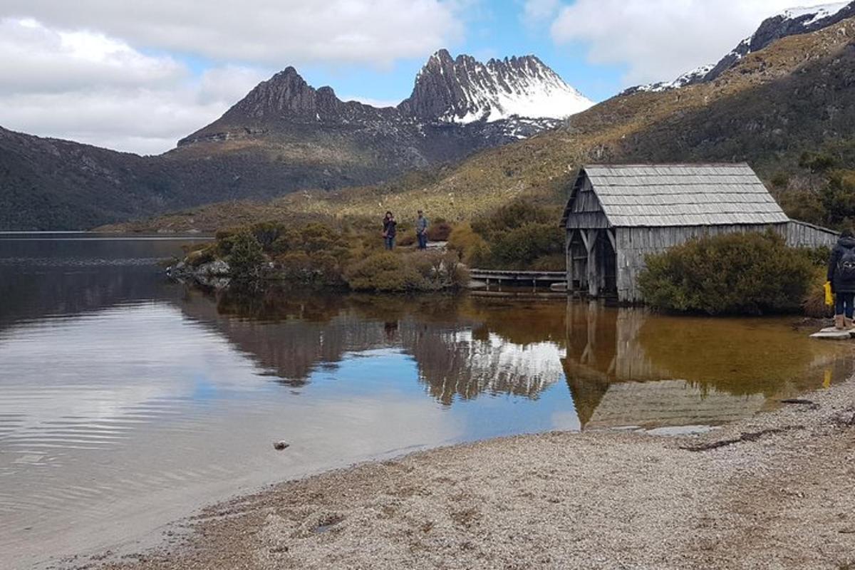 a barn on a lake with mountains in the background