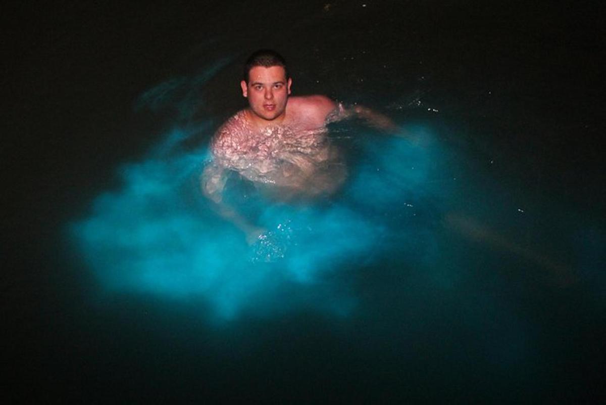 un uomo che nuota nell'acqua con luci blu