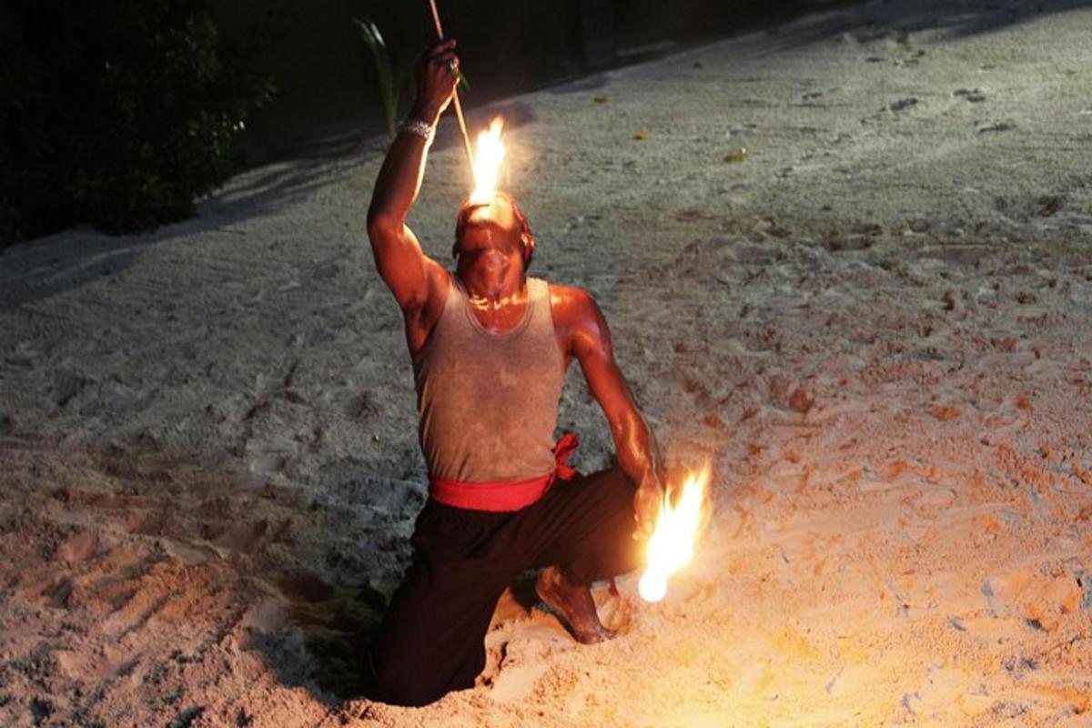un uomo che tiene in mano delle torce sulla spiaggia