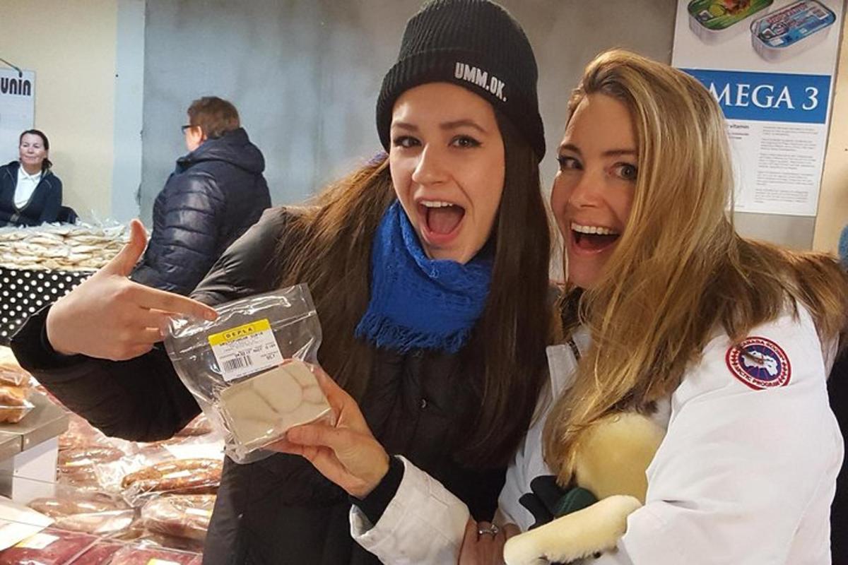 two women are laughing while holding a box of food