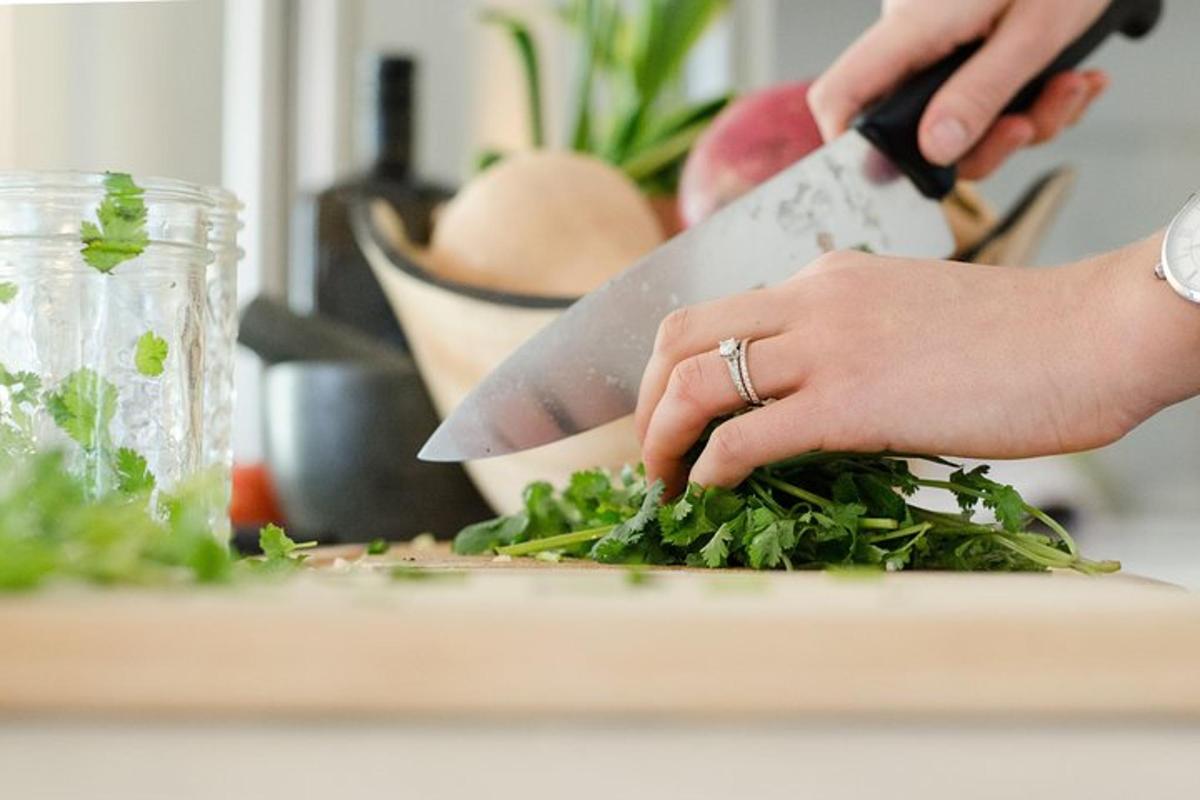 a woman cutting greens on a cutting board with a knife