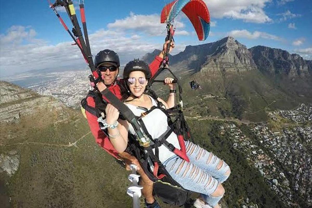 two people are riding a parachute on the mountain